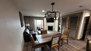 Un espace repas moderne avec une table et des chaises en bois, un canapé et une cheminée.