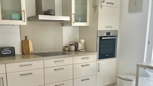 A modern kitchen with white cabinets, a stainless steel oven, and a herringbone-patterned floor.