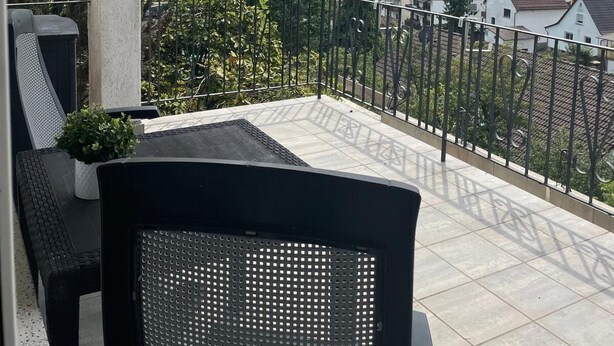 A balcony with a view of a green landscape and houses.