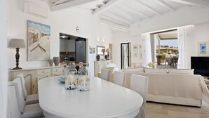 A spacious living area with a white round table, a sofa, and a view of the outdoors. - Villa Rita Luxury resort (Golfo Aranci)
