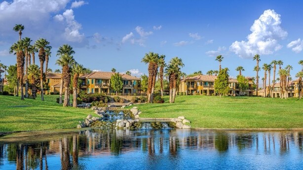 Ein Resort mit mehreren Gebäuden, einem Teich und Palmen.