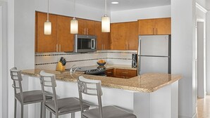Eine moderne Küche mit Holzausstattung, Edelstahlgeräten, einer Granitarbeitsplatte und Barhocker.