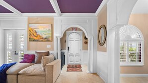 A living room with a beige sofa, a blue throw blanket, and a painting on the wall.