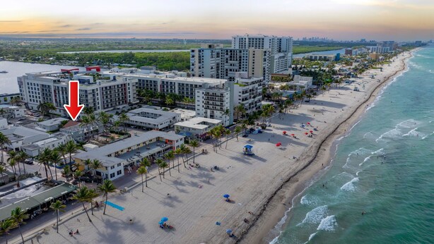 A coastal hotel with multiple high-rise buildings, a sandy beach, and a view of the ocean.