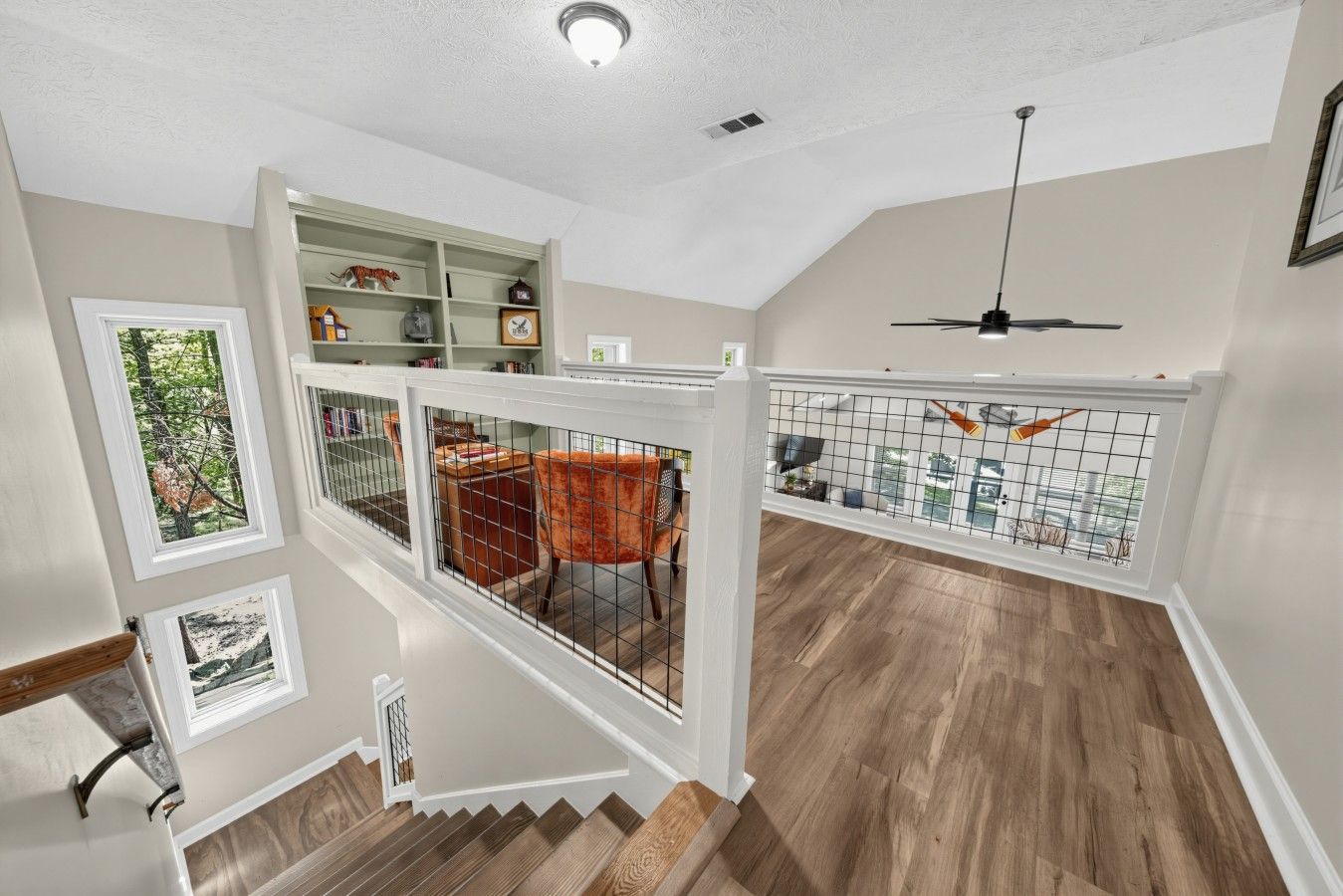 A multi-level interior with a staircase, a dining area, and a ceiling fan.