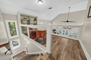 A multi-level interior with a staircase, a dining area, and a ceiling fan. - Lake Martin Dock House | Fire Pit, Game Room, Deck (Jacksons Gap)