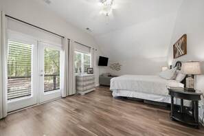 A bedroom with a bed, bedside tables, a dresser, a ceiling fan, and a TV mounted on the wall.