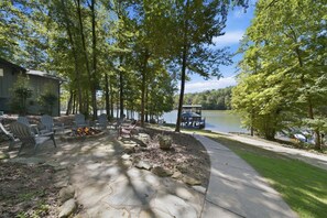 Une terrasse au bord du lac, avec des fauteuils Adirondack, un foyer et une jetée qui s’avance dans l’eau.