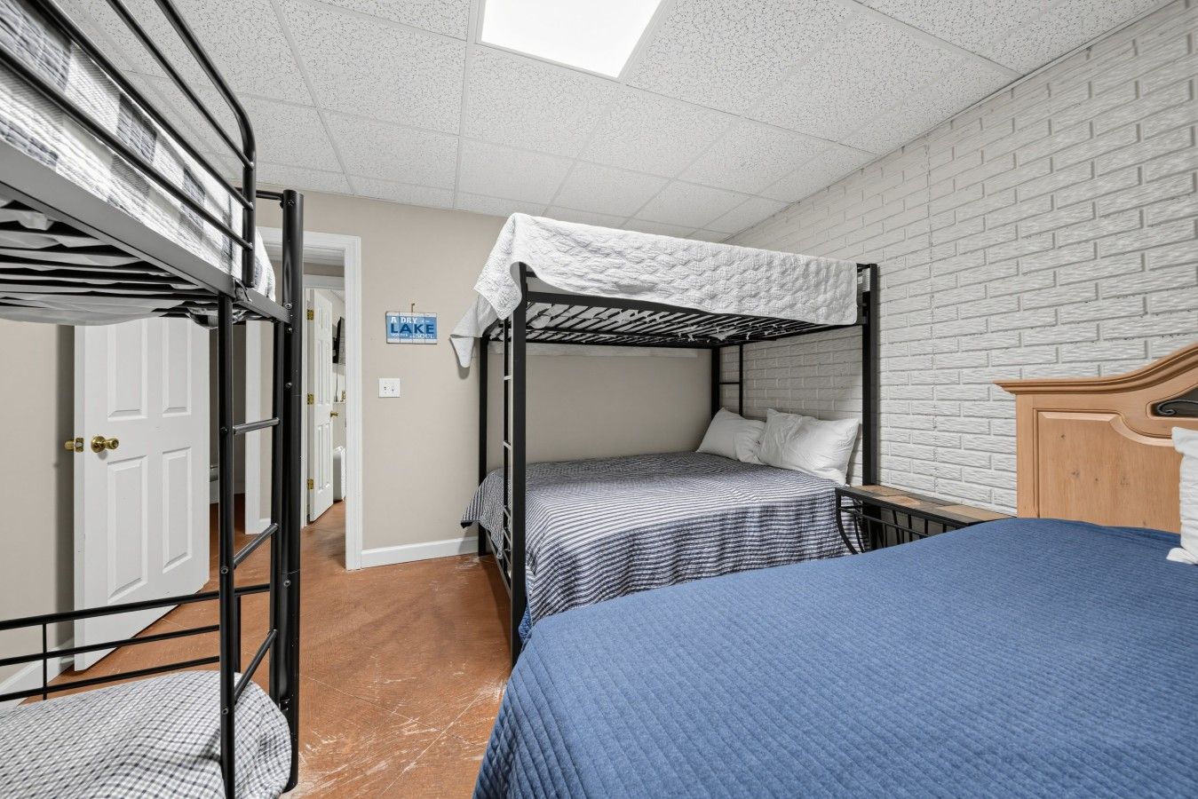 A bunk bed room with a skylight, a door, and a brick wall.