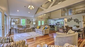 A spacious living room with a high ceiling, hardwood floors, and a dining area with a large table and chairs.