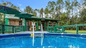 Uma piscina com deck de madeira e um edifício ao fundo.