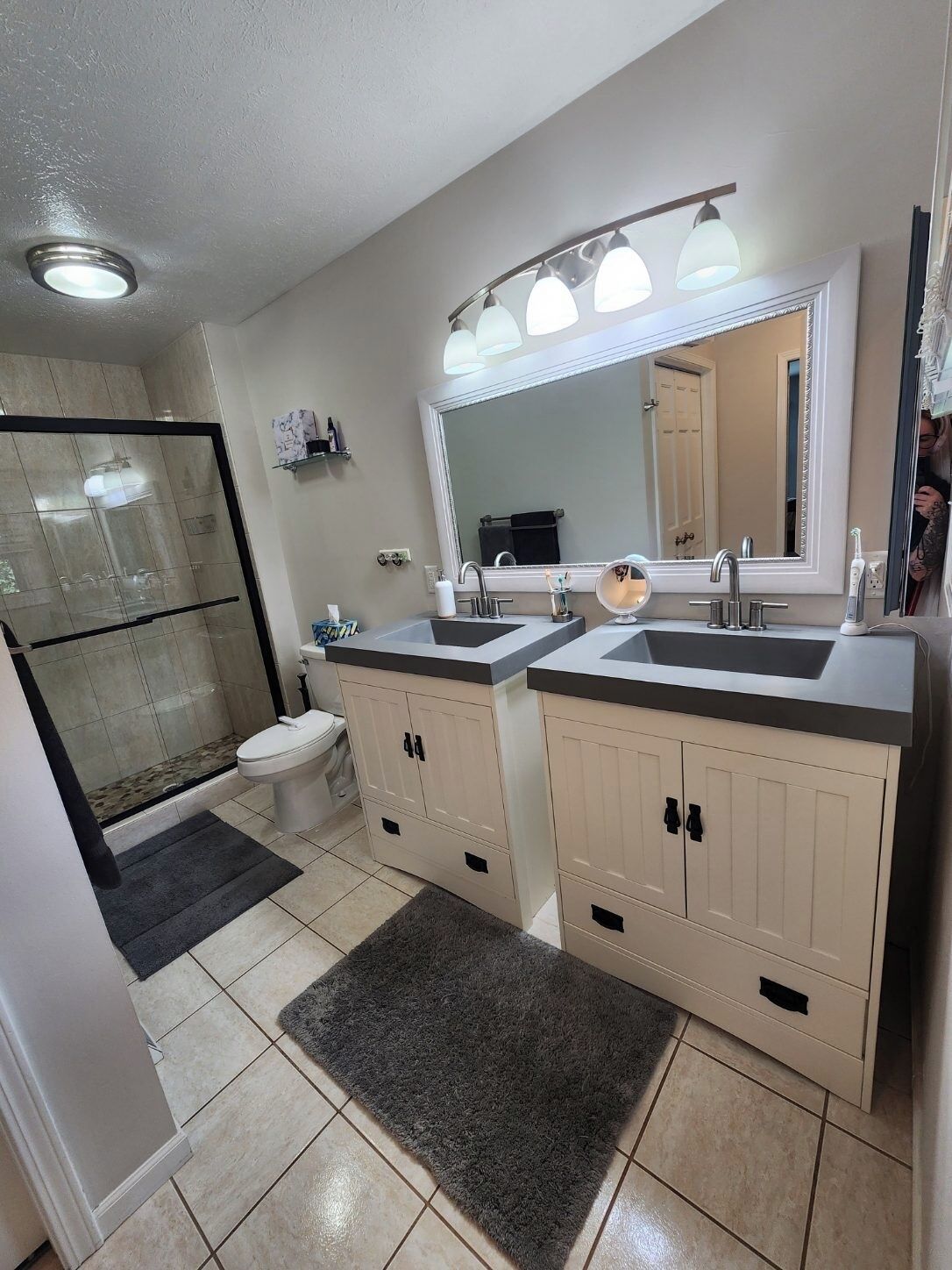A modern bathroom with a walk-in shower, a toilet, and a double sink vanity with cabinets.