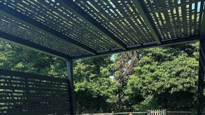 A covered outdoor seating area with a sectional sofa and a pergola overhead.