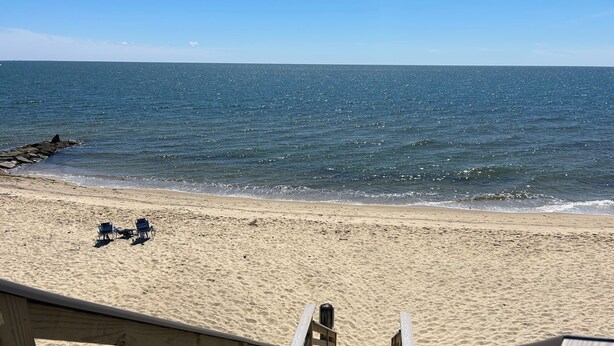 A wooden staircase leading to a sandy beach with two lounge chairs and a wooden railing. - Beautifully appointed 2 bedroom with access to a private beach! (DENNIS PORT)