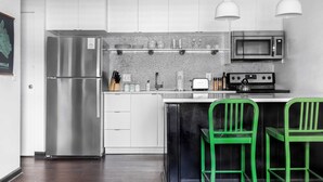 A modern kitchen with white cabinets, stainless steel appliances, and green bar stools. - Sleeps 8 4 Stylish Sobro Suites Near Music & Dining by Avantstay (Nashville)