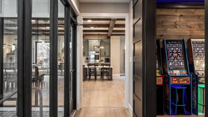 A modern kitchen with wooden beams, a dining area with chairs, and arcade games.