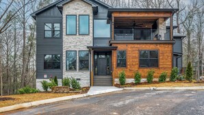 A modern two-story house with a stone facade, a wooden deck, and a garage.