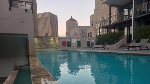 A swimming pool with lounge chairs, a view of a building with a dome, and a red circular sign.