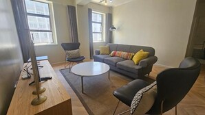 A modern living room with a sofa, armchairs, a coffee table, and a TV on a wooden stand.
