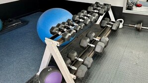 A gym with a blue exercise ball, a barbell, and a rack of dumbbells.