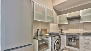 A compact kitchen with a refrigerator, washing machine, oven, and a microwave.