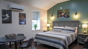 Een slaapkamer met een bed, bedlampen, een raam met een plant en een wandairconditioner.