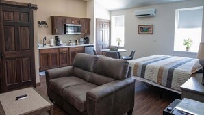 Een gezellig, compact ingerichte ruimte met kitchenette, een bank, een bed en een kleine tafel.