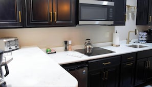 A kitchen with dark cabinets, a microwave, a toaster, and a coffee maker. - Trails to Ales Barrow Suite 5 (Franklin)