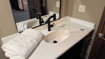 A bathroom with a white sink, a towel, a mirror, and a black faucet.