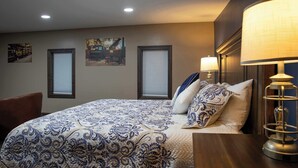 Un dormitorio con cama, dos lámparas de pared y dos ventanas con persianas.