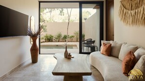 Un saló modern amb un sofà, una taula de centre i un gran finestral que ofereix vistes a una piscina i vegetació.