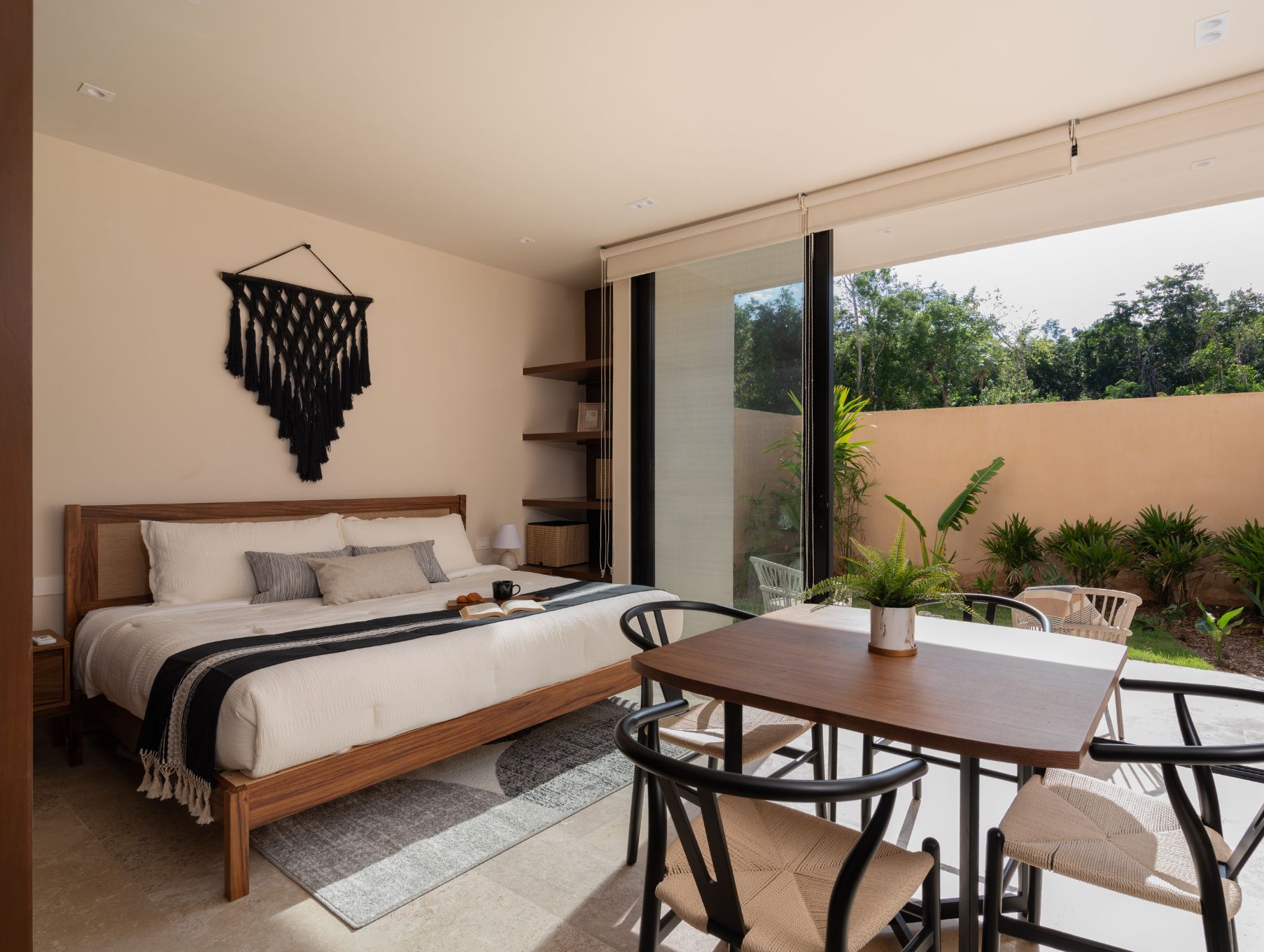 Ein Schlafzimmer mit Bett, Nachttisch und Blick ins Freie.