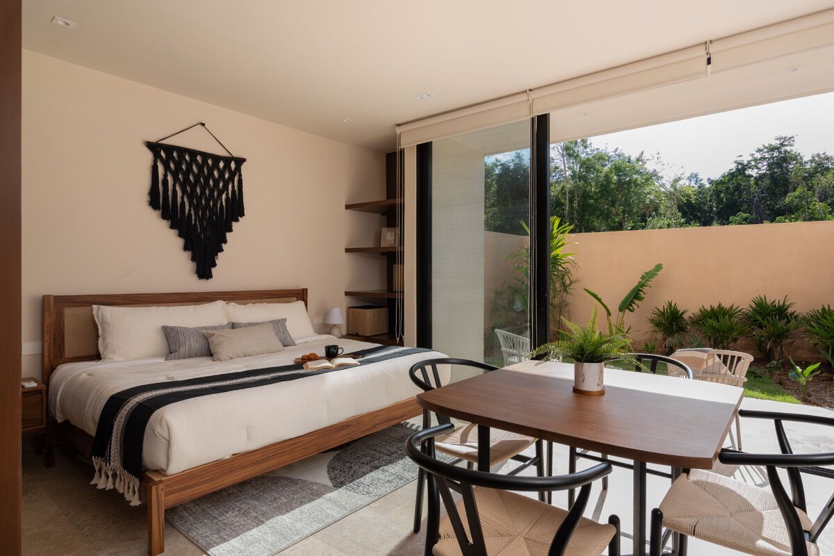 A bedroom with a bed, bedside table, and a view of the outdoors.