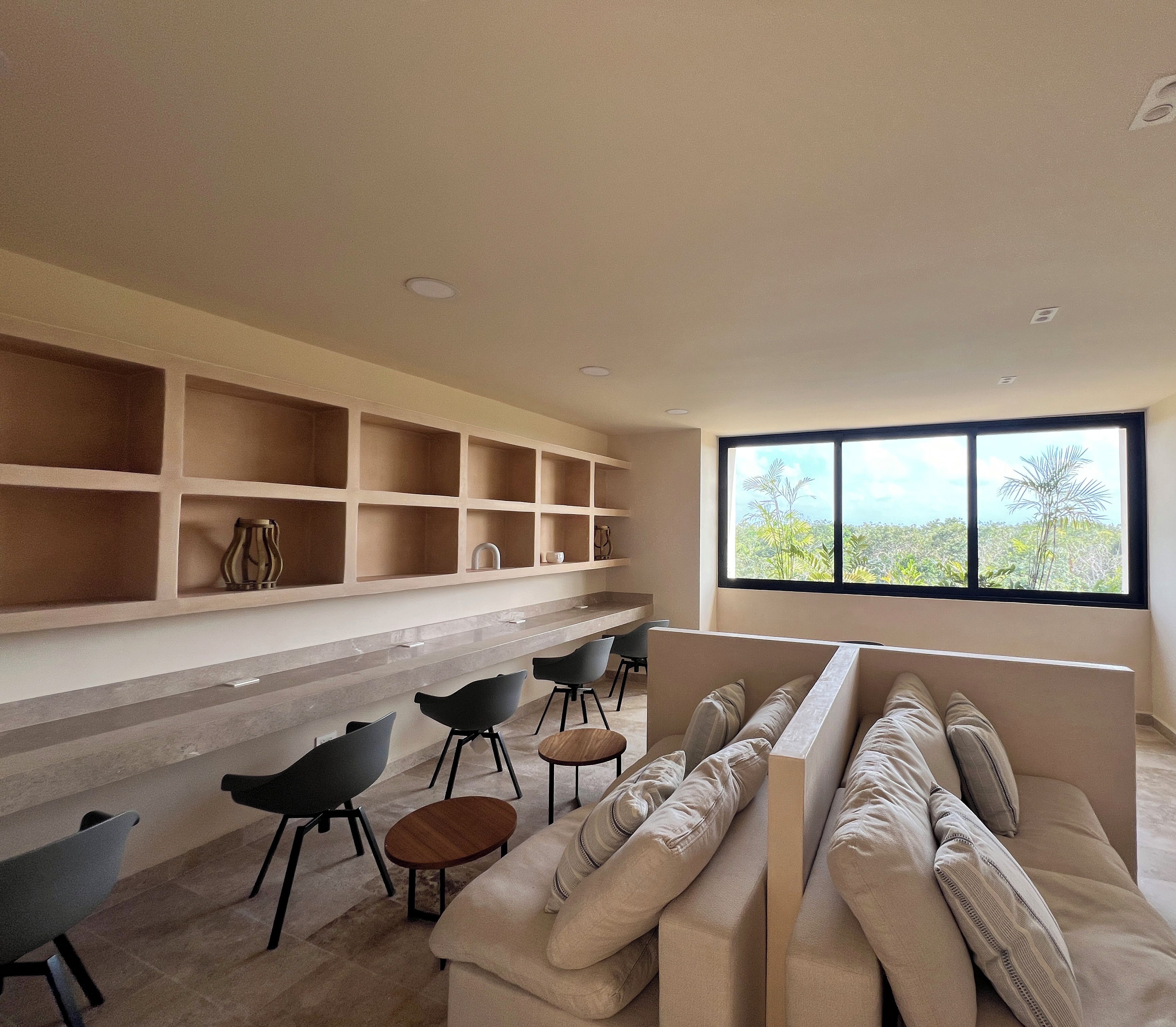 Un salon moderne doté d’une bibliothèque intégrée, d’une grande fenêtre offrant une belle vue, d’un canapé et d’une table basse.