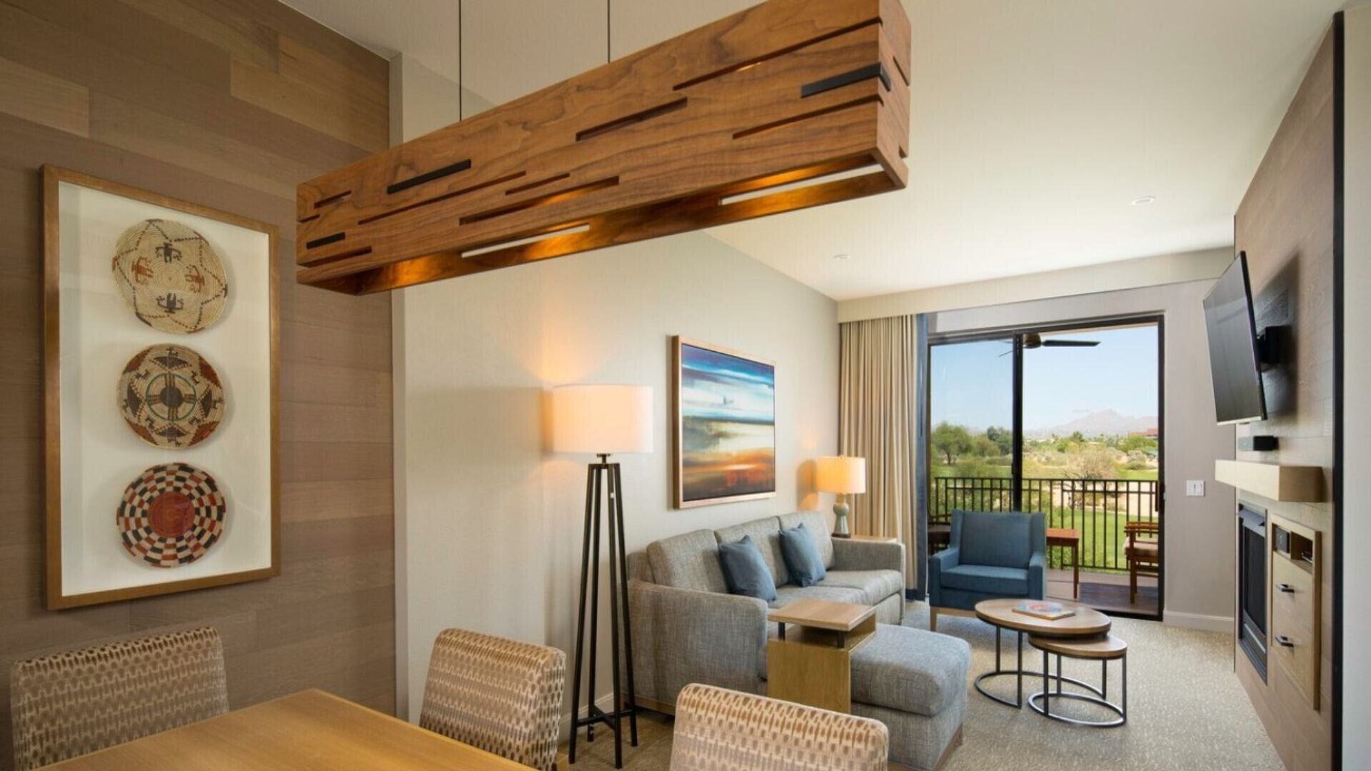 Una habitación de hotel moderna con techo de madera, un sofá, una mesa de comedor y un balcón con vistas.