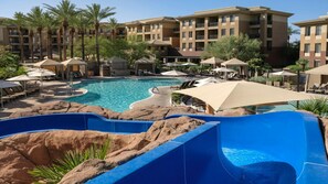 A resort with a large pool, palm trees, and a water slide.