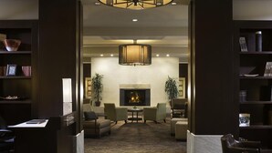 A hotel lobby with a fireplace, comfortable seating, and a bookshelf.