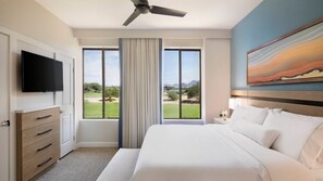 Ein Hotelzimmer mit einem großen Bett, einem flachbildfernseher an der Wand, einem Deckenventilator und einem großen Fenster mit Blick auf einen Golfplatz.