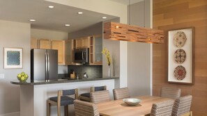 Una cocina moderna con electrodomésticos de acero inoxidable, una isla de madera y un comedor con sillas de mimbre y una mesa de madera.