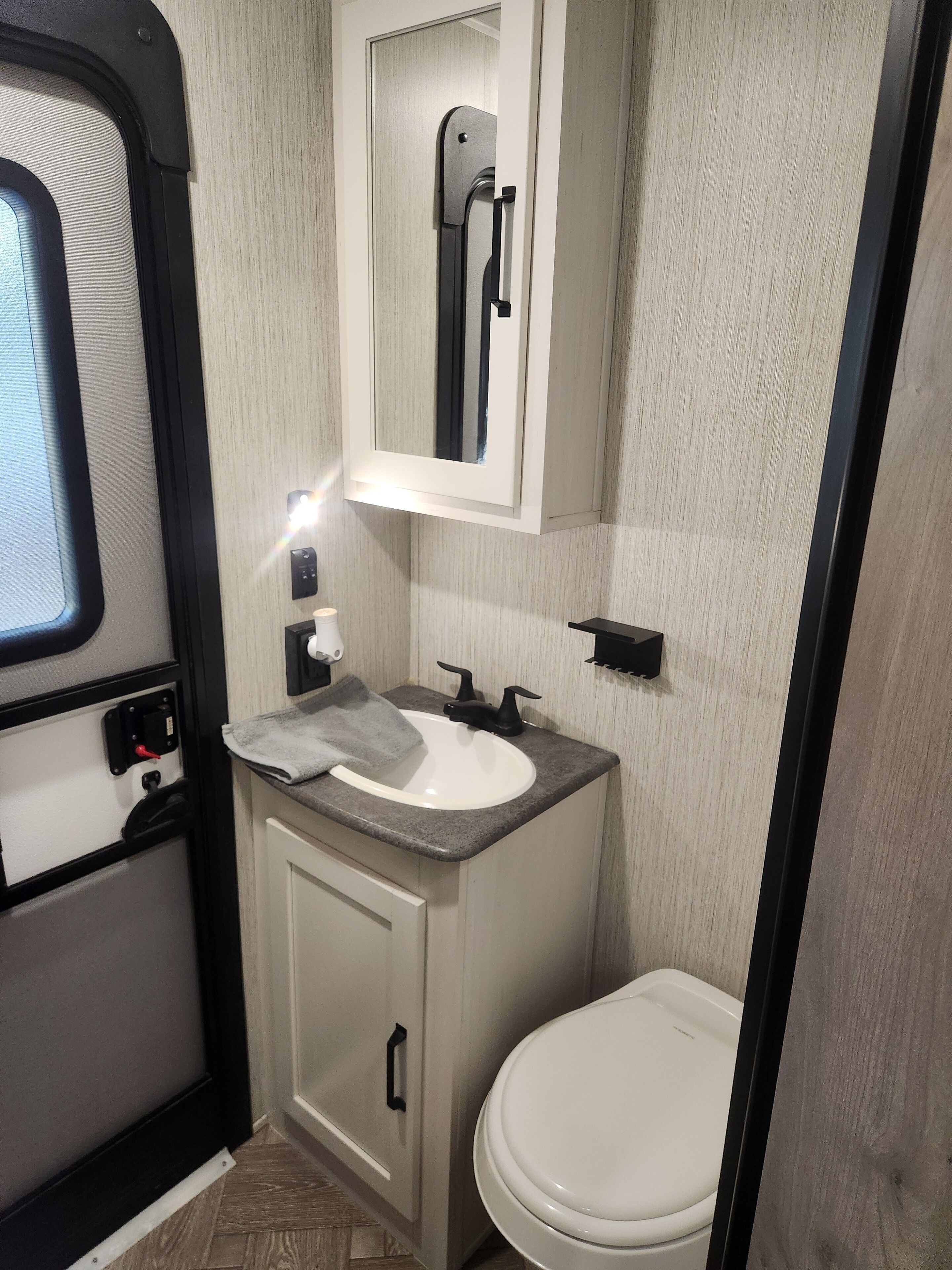 A compact bathroom with a white sink, a mirror above it, and a toilet.