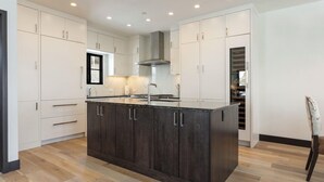 Una cocina moderna con armarios de madera oscura, una isla central y luces empotradas en el techo.