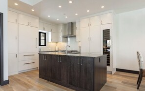 Una cucina moderna con mobili a legno scuro, un'isola centrale e faretti a soffitto.