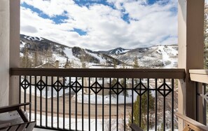Un balcone con ringhiera in metallo affaccia su un paesaggio montano innevato.
