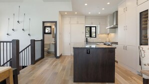 Una cocina moderna con armarios blancos, una isla central y una escalera de madera.