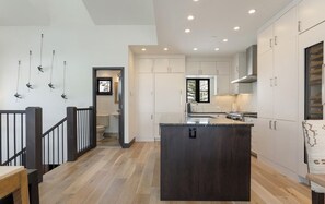 Una cucina moderna con mobili bianchi, un'isola centrale e una scala in legno.