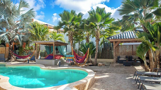 A swimming pool surrounded by palm trees and outdoor seating areas. - All Seasons by Boutique Bonaire Unique Resorts (Kralendijk)