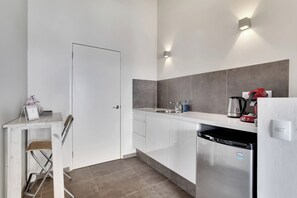 A modern kitchen with white cabinets, a stainless steel refrigerator, a sink, and a countertop with a kettle and a red appliance. - All Seasons by Boutique Bonaire Unique Resorts (Kralendijk)