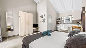 A modern bedroom with a bed, a wardrobe, a television, and a kitchenette.