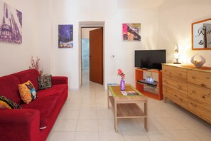 A living room with a red sofa, a wooden coffee table, a TV, and a wooden cabinet.