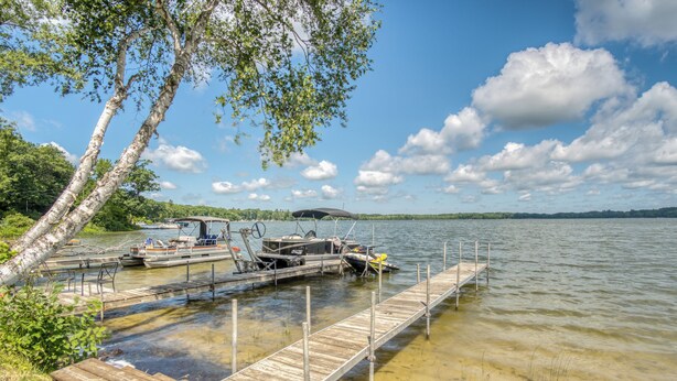A wooden dock extending into a calm lake with boats docked at the end. - Cozy Log Cabin with Dock, Kayaks, Firepit, AC, minutes to Ludington and Lake MI (Fountain)
